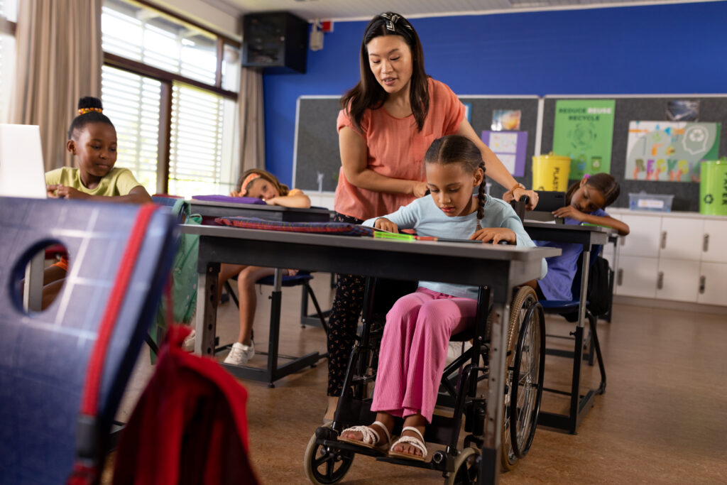 female teacher and schoolgirl in wheelchair in elementary school class
