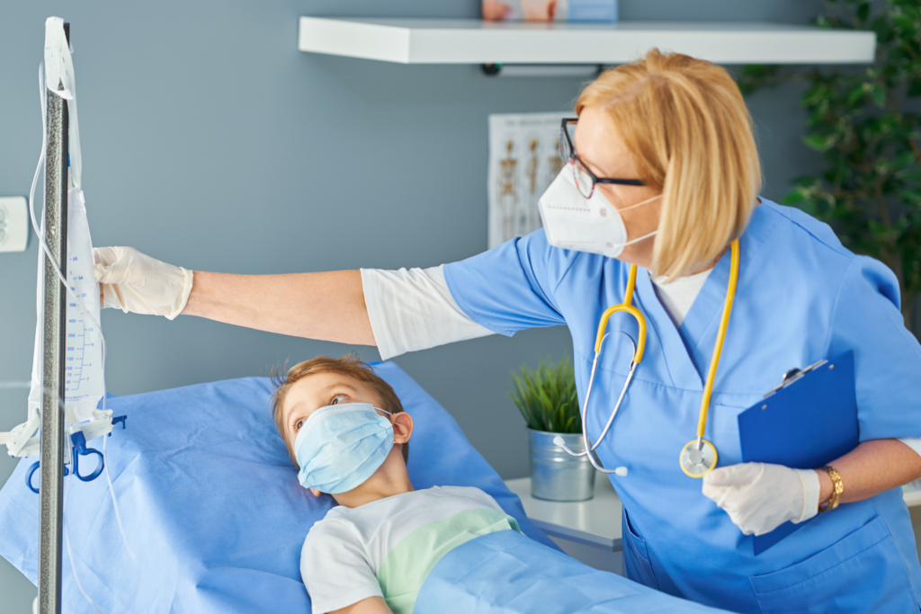 Image of a young boy in a hospital bed and a nurse checking on him.