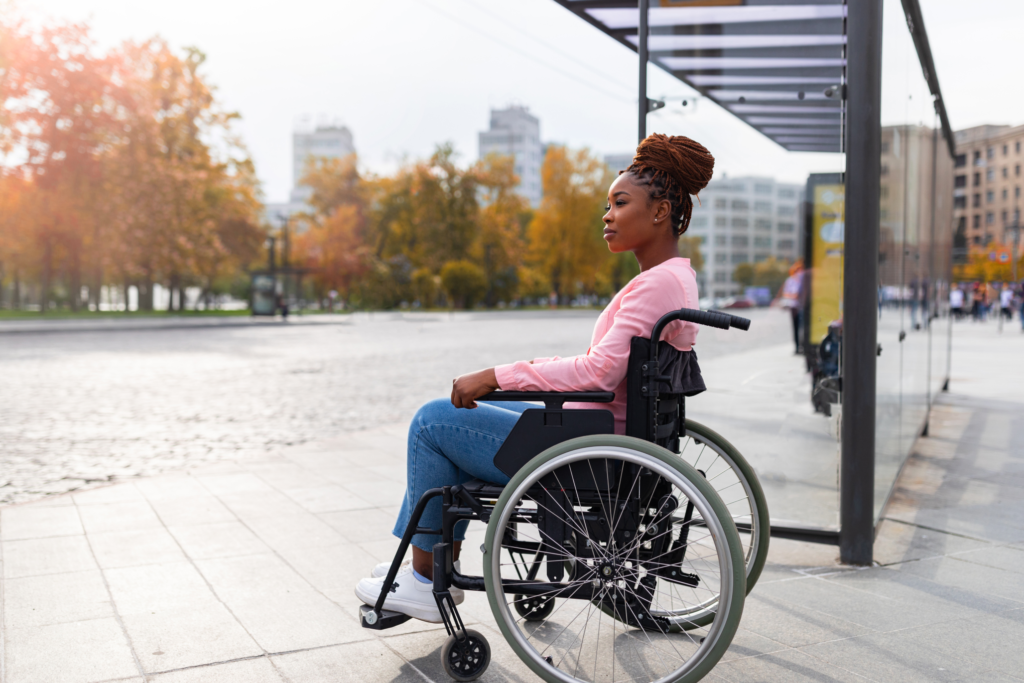 Image of a young woman in a wheelchair waiting for a bus