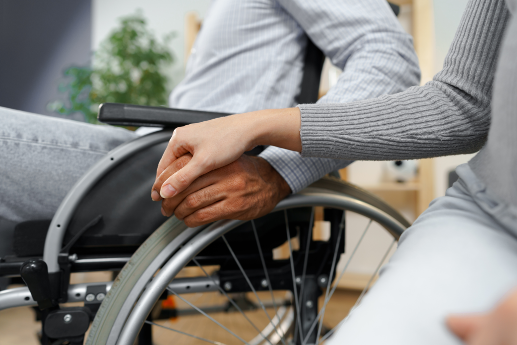 Close up Image of a woman touching the hand of a disabled man