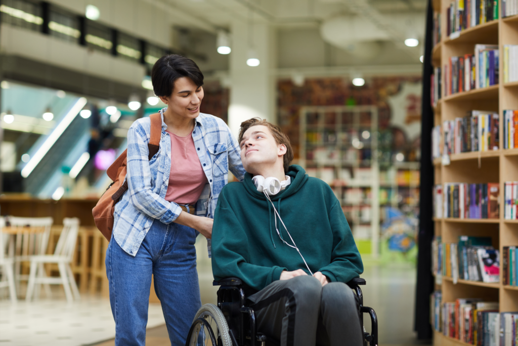 Image of a young person in a wheelchair and their carer