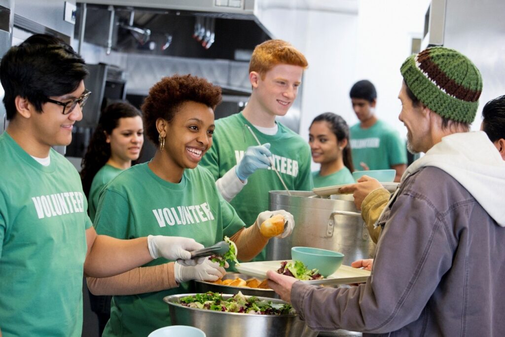 Young people in green top handing out food from containers