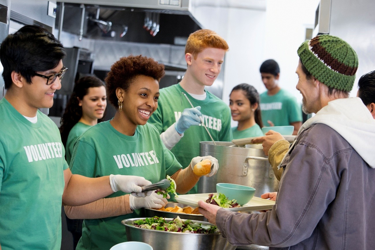 Young people in green top handing out food from containers